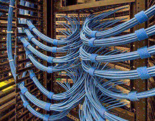 A close-up view of blue network cables neatly bundled with SPEEDWRAP® Cable Ties inside a server room rack.