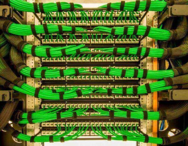 Rows of green Ethernet cables are bundled and connected to network switches with SPEEDWRAP® Cable Ties, creating a neat and organized server rack.