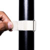 A hand secures a SPEEDWRAP® High Temp Cinch Strap around a black cylindrical pole against a white background.