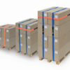 Three stacks of cardboard boxes secured with VELCRO® Brand LOGISTRAP® Pallet Straps sit on wooden pallets, arranged from shortest to tallest, against a plain white background.