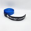 A rolled blue VELCRO® Brand LOGISTRAP® Pallet Strap with a black end piece featuring the brand logo, set against a plain white background.