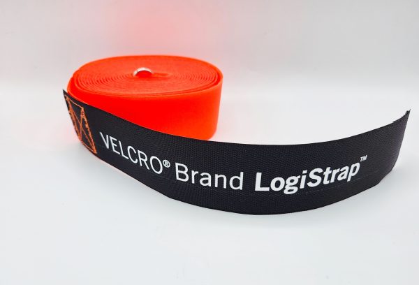 A rolled-up orange VELCRO® Brand LOGISTRAP® Pallet Strap with a black end labeled in white, displayed on a plain white background.